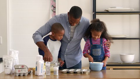 Father And Children Baking Cakes In Kitchen Together