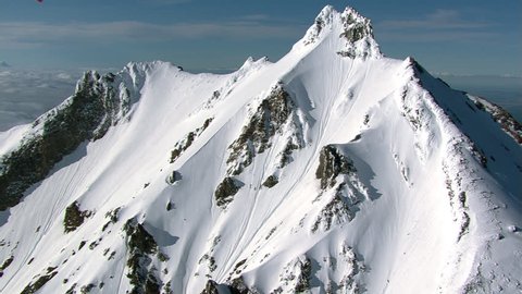 Aerial zoom-out from snowy peak in Cascade Range