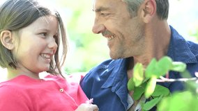Daddy with girl in garden looking at flower buds
