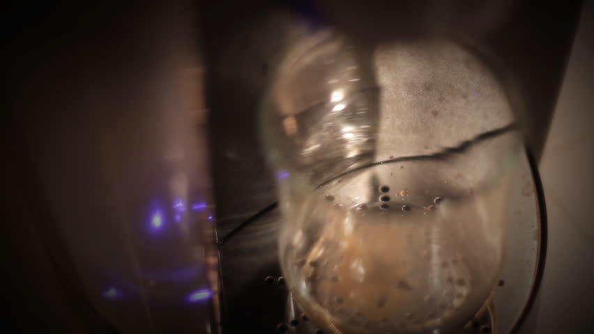 A close up, shallow focus shot of a clear glass being filled with coffee from a