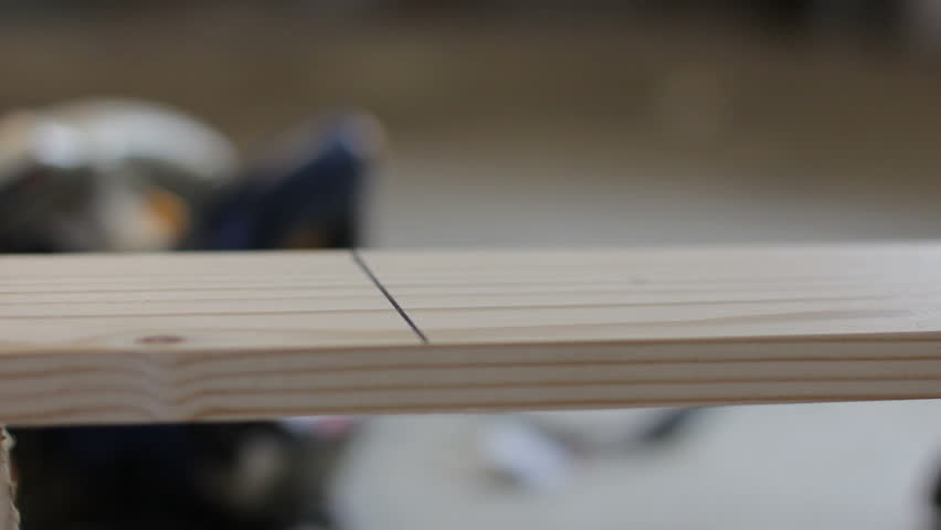 Close up shot of a high tech hand skill saw cutting a board in half.