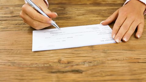 Close-up Of A Businesswoman Giving The Signed Blank Cheque To A Person In Office