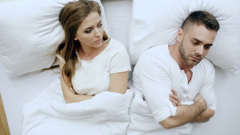 Top view of young upset couple lying in bed have problems after quarrel and angry each other at home