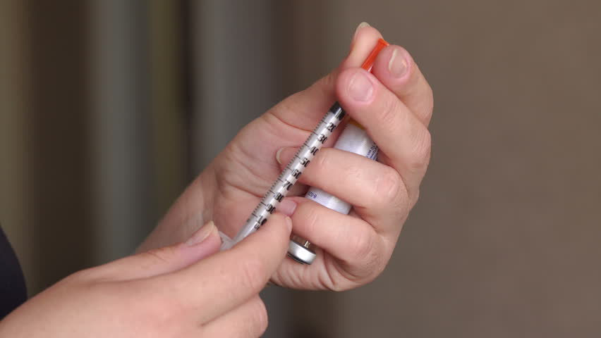 Close-up of a woman removes the cap from the insulin syringe. | Shutterstock HD Video #26754526