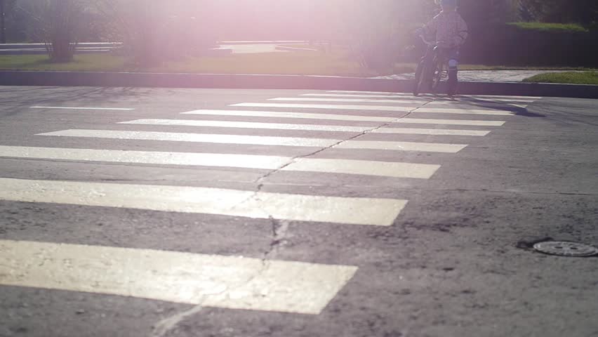 A small child on a bicycle crosses the pedestrian crossing