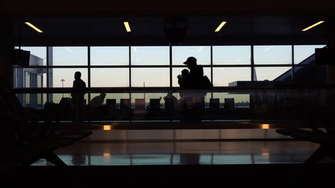 Airport terminal people silhouette against morning sunrise out window. Walk through security gate area to wait for flight departure 4K stock video