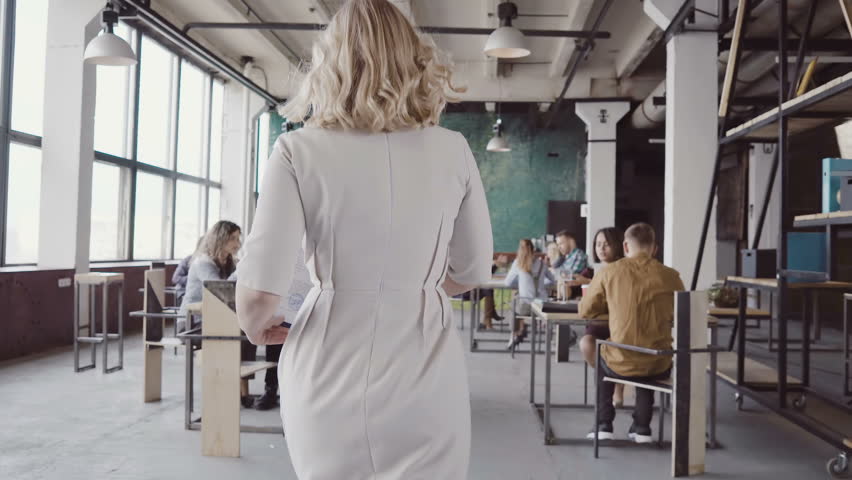 Beautiful blonde female team leader walks through the office, controls the work of employees, gives direction to colleague. Royalty-Free Stock Footage #26767045