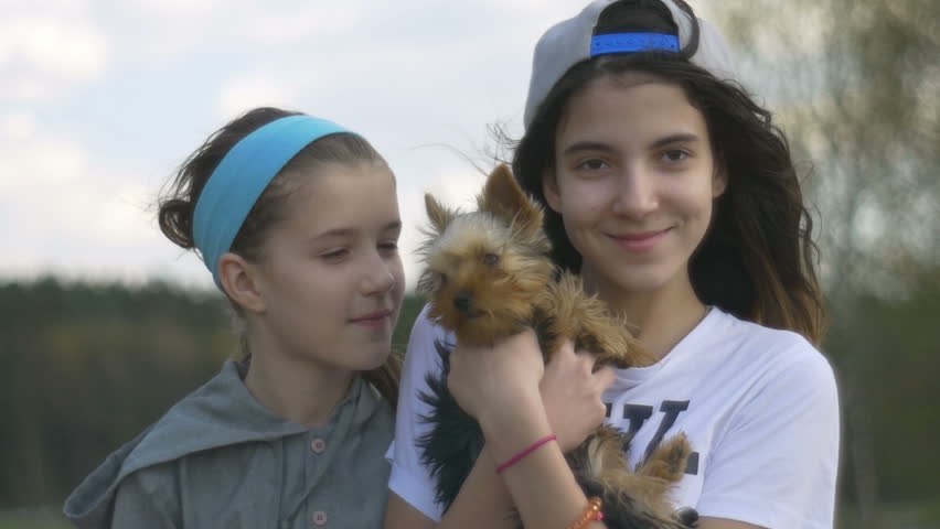 Two girls, a teenager and a child hug their beloved puppy