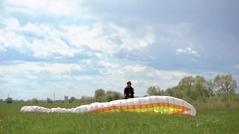 Male paraglider, checks equipment on the ground. Safety is important for flying in the sky.