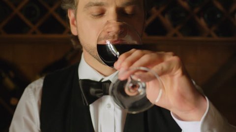 Sommelier is tasting red wine on wood background. Close up. Slow motion.