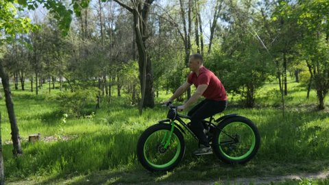 KHERSON, UKRAINE - APR 20, 2017: Man Riding Electric Bicycle In A Green Park Grass