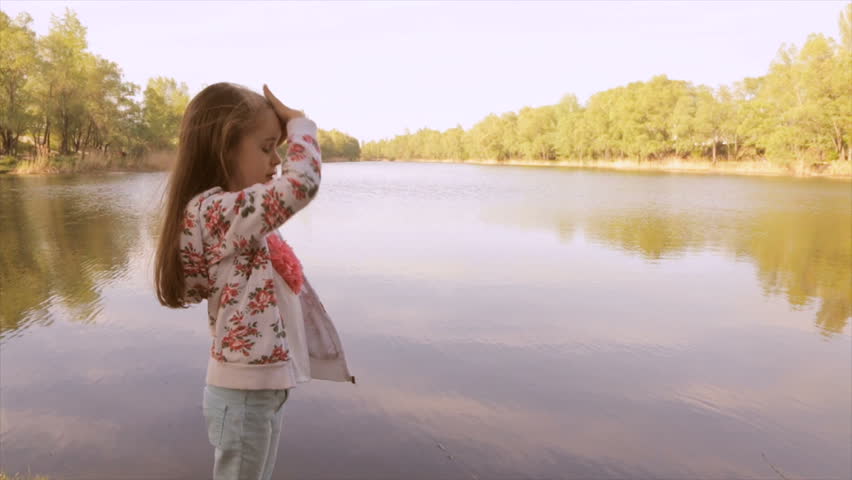 Girl stroking her hair and looking at the lake