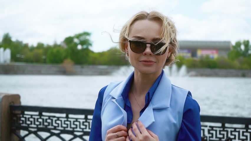 Beautiful business woman in a blue shirt, near the rivers. Going to a meeting, smiling happily
