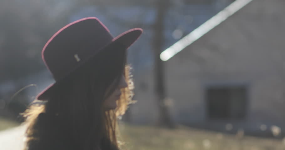A young girl waiting in the park outdoors for someone, she is looking at her watch and looks worried