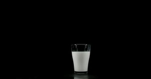 Egg falling into a Glass of Milk against Black background, Slow motion 4K