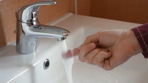 Man checking temperature of tap water by hand