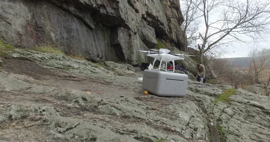 Drone on stone against backdrop of mountaineer man gathering equipment