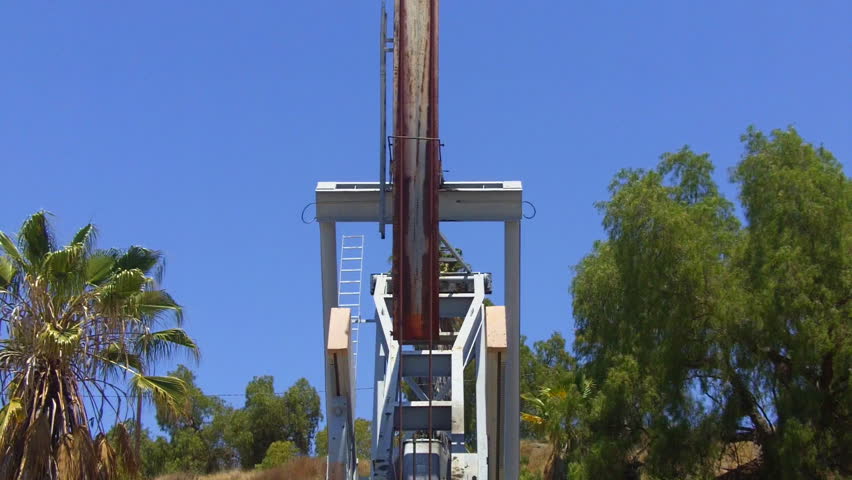 A low angle, head-on shot of an oil well pump jack extracting petroleum from the