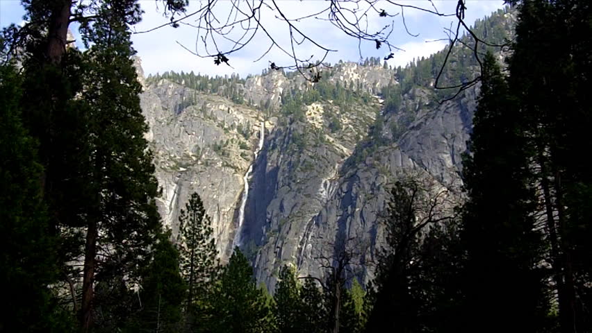 The sheer granite cliff faces of mountains framed by huge pine trees in the