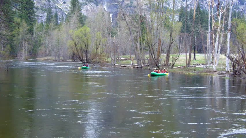 Two rafts with adult passengers float toward the camera on the Merced river in