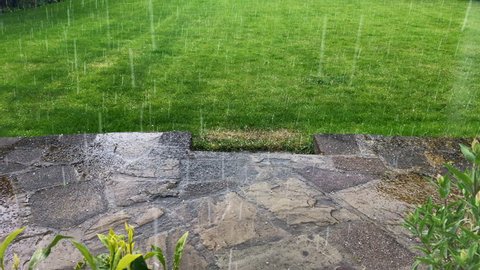 Hailstone ice particles precipitation patio stone paving green grass garden summer thunderstorm extreme weather