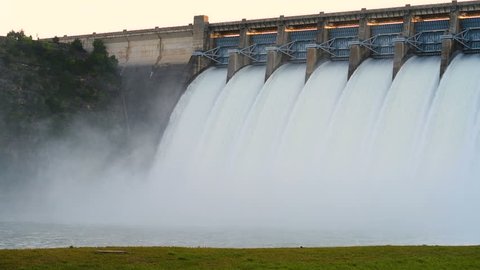 Large lake dam with gates open flowing a large amount of water.   