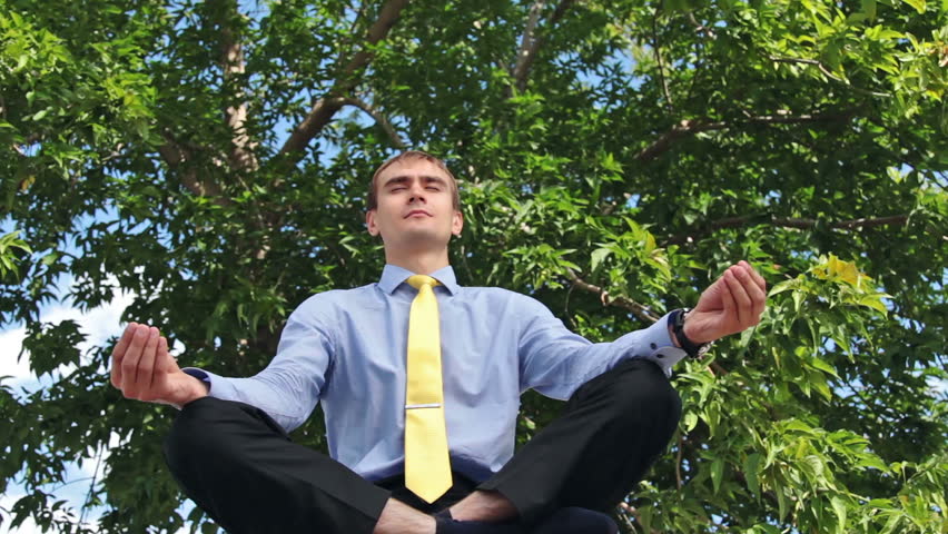 Young businessman doing yoga in the park
