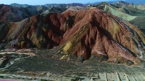 Flying a drone over the colorful Zhangye Rainbow Mountains; aerial view on sandstone hills and mountain chains covered by amazing pattern. Part 1 of a continuous 5 part series.