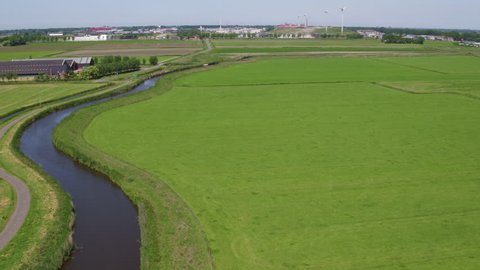 Drone aerial footage of Dutch Windmill in countryside agricultural landscape of Holland with cyclists passing 