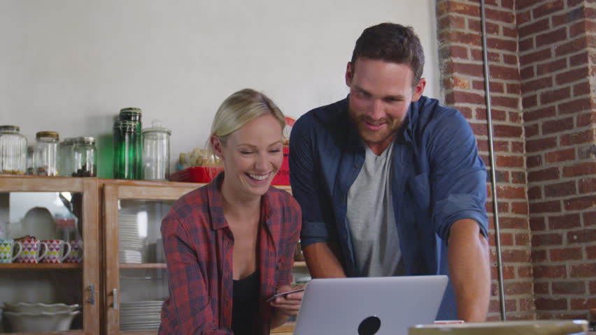 Young white couple on-line shopping in kitchen, waist up, shot on R3D