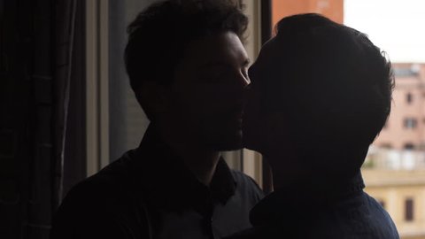 Silhouette of men at the window kissing