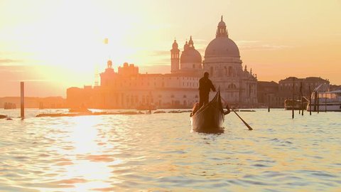 VENICE, ITALY-CIRCA 2011-A gondola is rowed by a gondolier in front of the setting sun in romantic Venice, Italy.