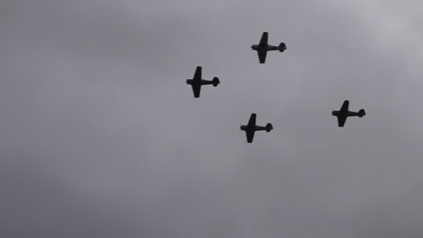 Silhouette of four Supermarine Spitfire is a British single-seat fighter fly in formation over a dark cloudy grey sky used by the Royal Air Force before, during, and after World War II.
