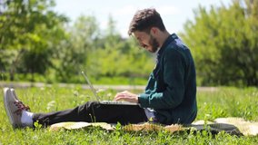 man using laptop in park on a summers day