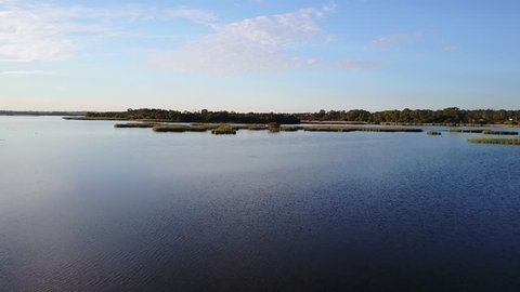 Panoramic aerial view of scenic flight above wetlands lake in Perth, Western Australia, with sunny blue sky and horizon, clear water, forest along shore, natural background and copy space.
