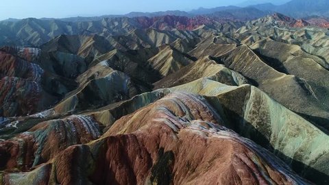Flying a drone over the colorful Zhangye Rainbow Mountains; aerial view on sandstone hills and mountain chains covered by amazing pattern. Part 2 of a continuous 5 part series