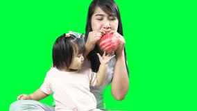 asian young pretty mother play balloon her little baby with love on green screen