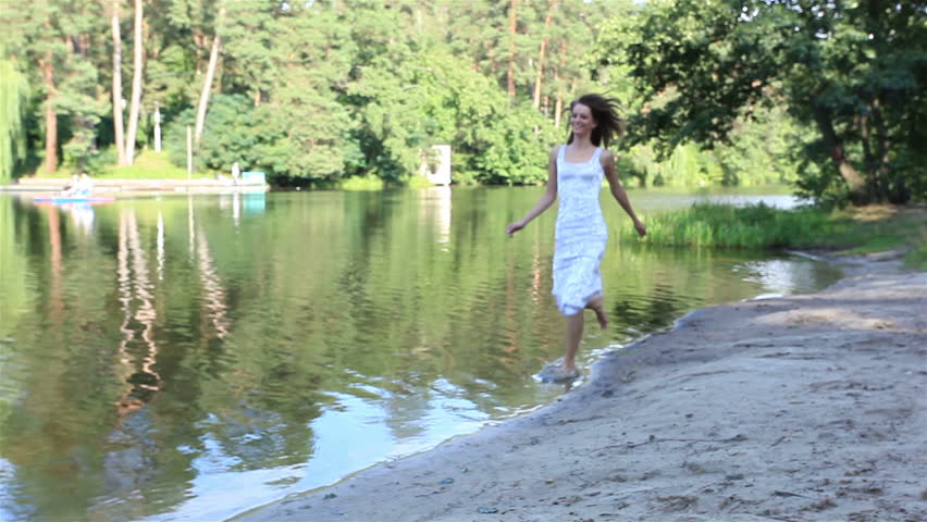 beautiful girl goes on the lake coast