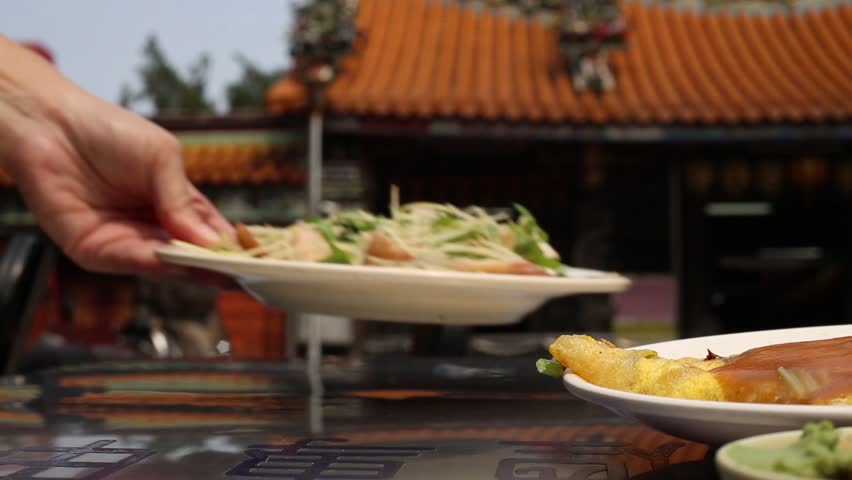 One person is putting plates with food at the Ci Sheng Temple open air restaurant in Taipei, Taiwan. Tzu Sheng Temple is a small temple in Tataocheng, one of Taipei's oldest neighborhoods. | Shutterstock HD Video #26868901