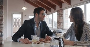 young caucasian couple in love talking while having italian breakfast and american coffee indoor in modern industrial house.4k handheld video shot