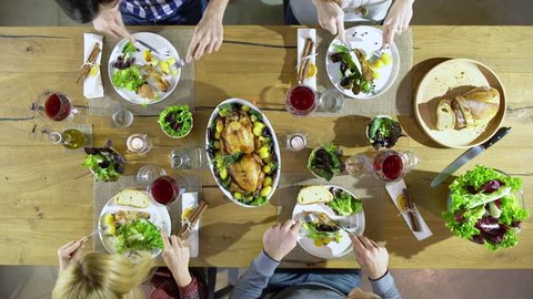 Overhead top view table four caucasian friends eating lunch, drinking, toast together with chicken,sala, potatoes, red wine. in modern house home. 4k video