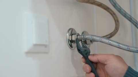 A plumber installs water heater hose.