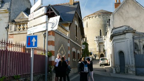 AMBOISE, FRANCE - CIRCA 2017: People visiting French city of Amboise standing on Victor Hugo Rue street with the huge tower of Chateau d'Amboise - deciding to go to the nearby Clos Luce castle