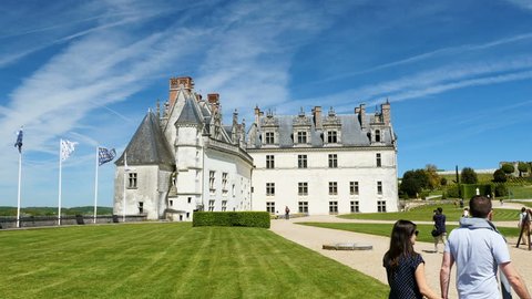 AMBOISE, FRANCE - CIRCA 2017: People tourists visiting the majestic Amboise Chateau castle - The royal Castle of Amboise flags heraldry Fleur de lis and Ermine against dramatic sky