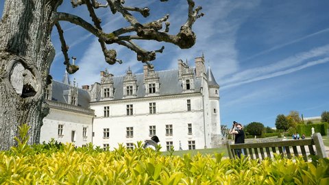 AMBOISE, FRANCE - CIRCA 2017: People visiting the majestic Amboise Chateau castle - woman reading on park bench while photographer takes a picture of the tree