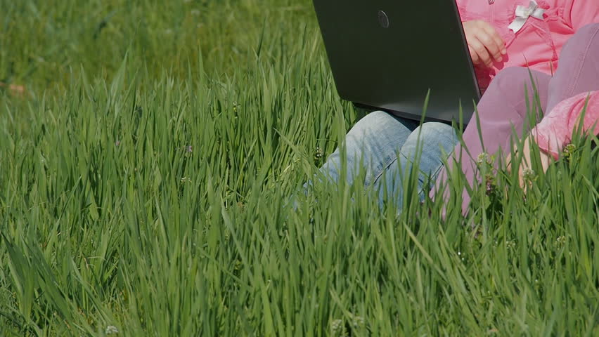 Woman with children in nature with laptop. Mom and daughters on the green lawn. Children in pink. Happy family in nature on a sunny day. Family in the park.