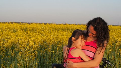 Child with hugging mother. Family in nature. a happy family. A woman with a child on a rapeseed field. Slow motion.