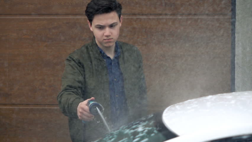 Young, teenage boy washing car with hose, super slow motion 240fps
