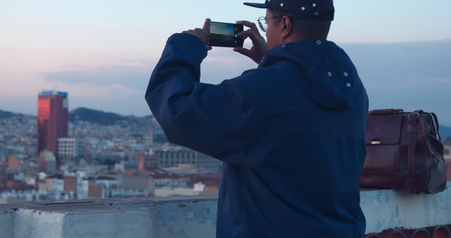 african american traveler makes a city panorama photos on smartphone evening time