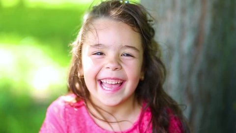 Closeup portrait of beautiful cute brunette caucasian little girl smiling and laughing while looking at camera. Real time full hd video footage.